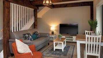 A living room with a sofa, a coffee table, a TV, and a staircase.