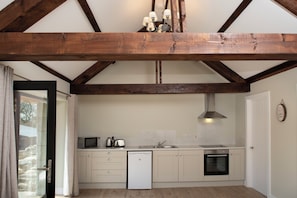 A kitchen with wooden beams, a microwave, toaster, sink, and a dishwasher. - K2Cottages (Newtownmountkennedy)