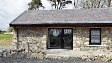 A stone building with a sloped roof, large windows, and a stone foundation.