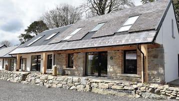 A stone building with multiple windows and a sloped roof.