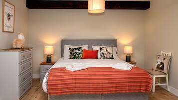 A bedroom with a large bed, two bedside tables with lamps, a dresser, and a chair.