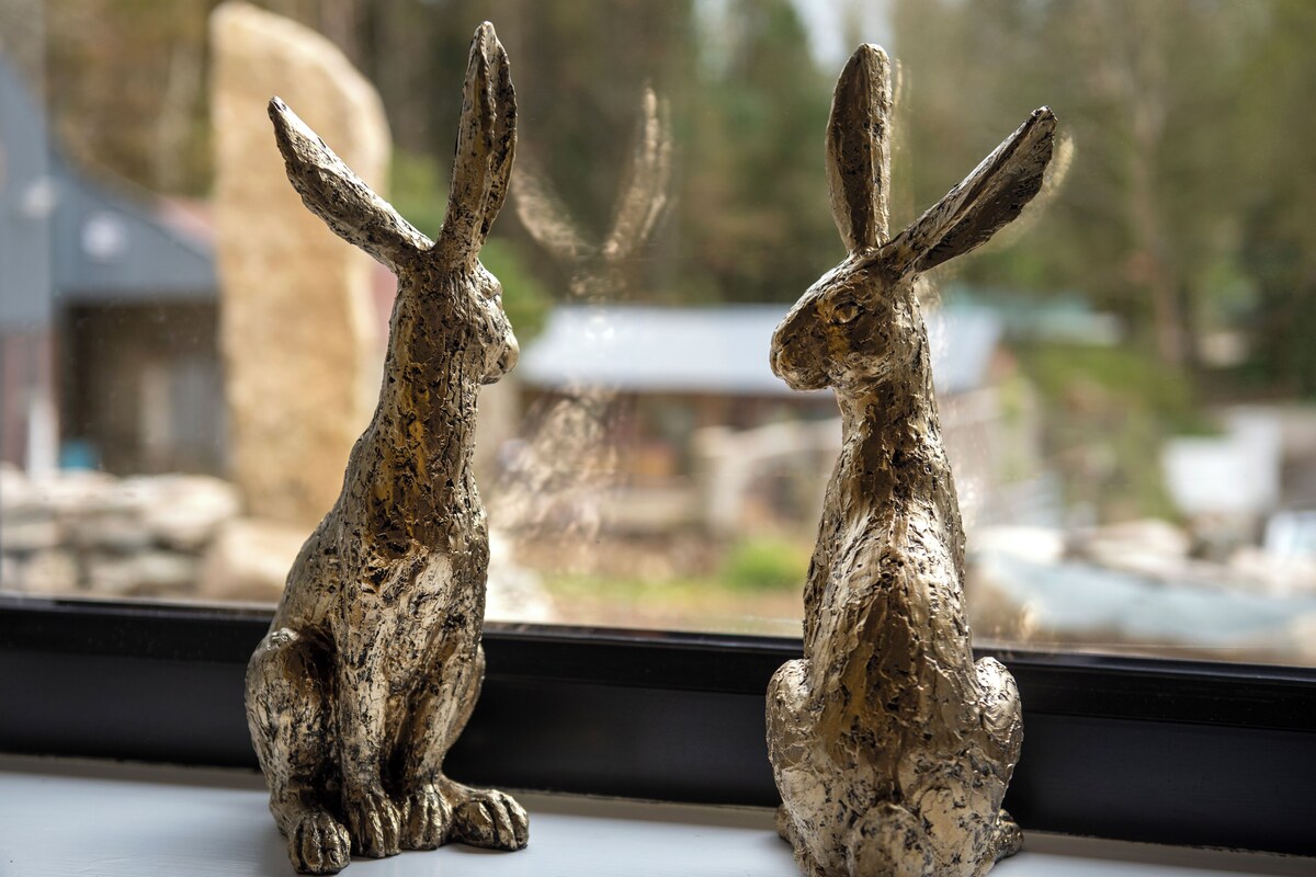 Two rabbit figurines on a windowsill.