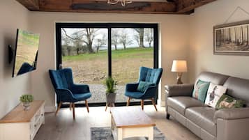 A living room with a large window, two blue chairs, a sofa, a coffee table, and a painting on the wall.