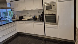 A modern kitchen with white cabinets, a Bosch microwave, and a coffee machine. - Guesthouse 'Eifelglück' with Private Terrace, Garden, and Wi-Fi (Großlittgen)