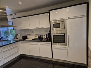 Een moderne keuken met witte kasten, een Bosch magnetron en een koffieapparaat.