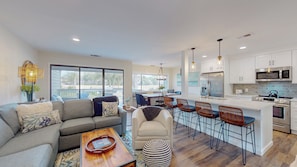 A modern living room with a sofa, coffee table, and a dining area with chairs and a table. - Beautiful Three Bedroom Villa with Sweeping Views of George Fazio Golf Course (Hilton Head)