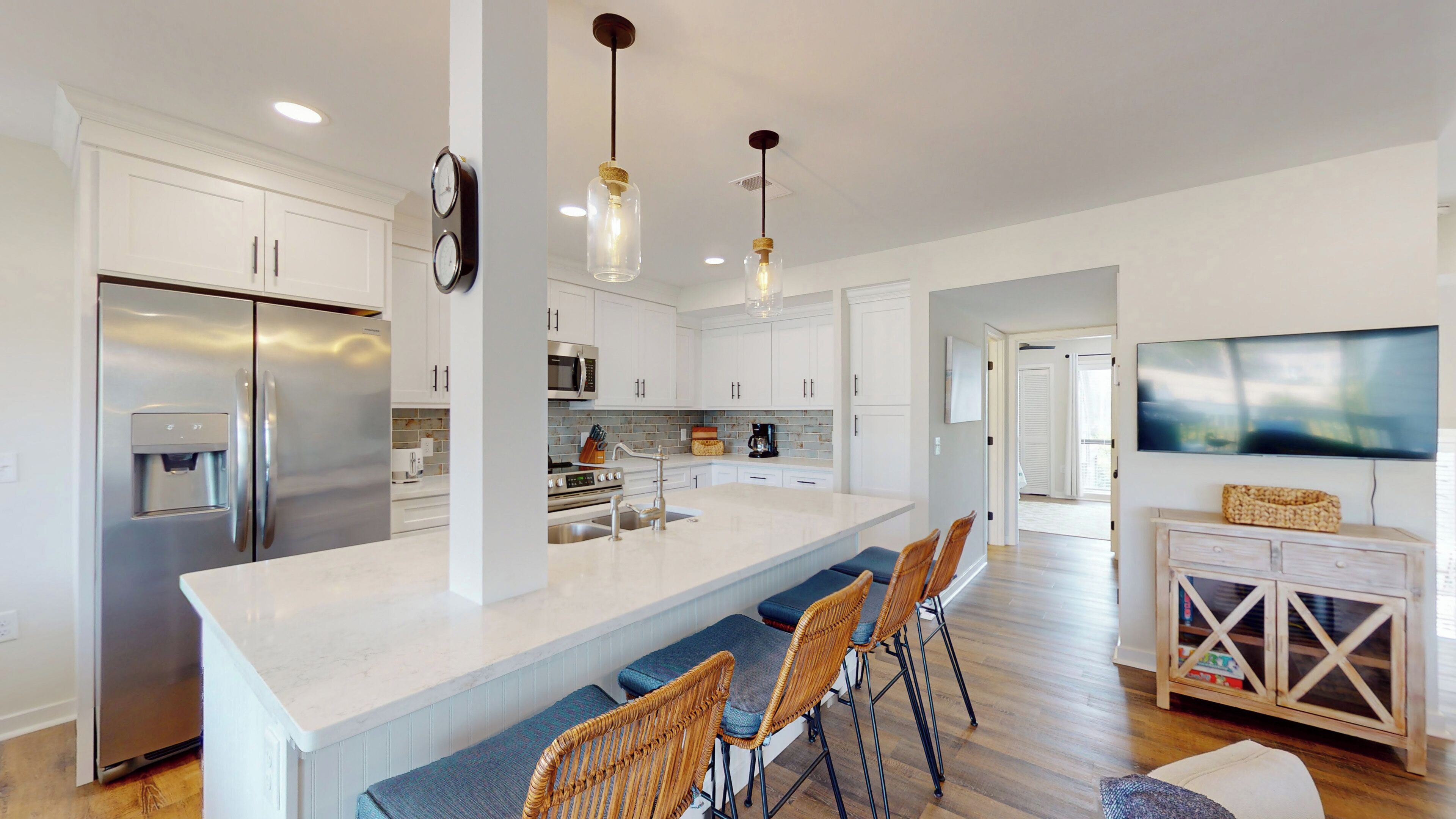 A modern kitchen with a central island, stainless steel appliances, and a dining area with wicker chairs.