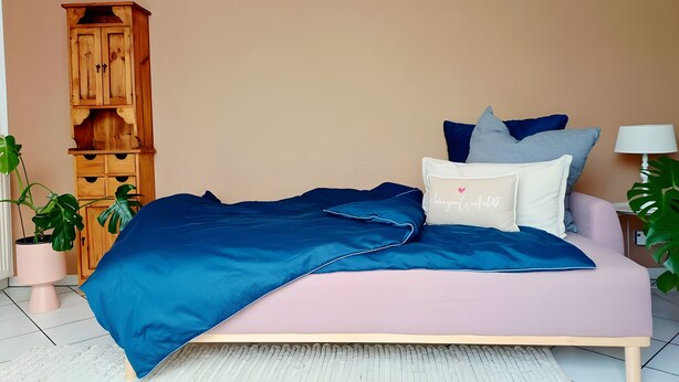 Ein Schlafzimmer mit einem Bett, einem Holzschrank und Topfpflanzen.