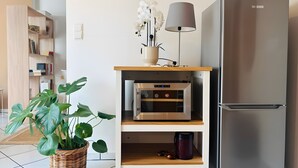 Eine moderne Küche mit Einbauofen, Edelstahlkühlschrank und einer Topfpflanze.