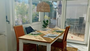 Ein Essbereich mit einem Holztisch, gedeckt für vier Personen, umgeben von Stühlen, und einer Hängeleuchte darüber.