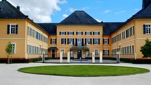 Ein großes, symmetrisches Gebäude mit einem zentralen Eingang, umgeben von einem gepflegten Rasen.