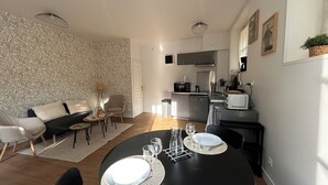 A compact living space with a dining area, kitchenette, and a patterned wallpaper. - LE REFUGE DU MOULIN - 2-Bedroom Apartment in Downtown Senlis (Parking) (Senlis)