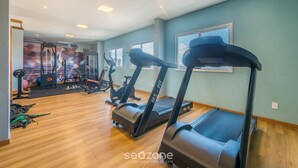 Academia com esteiras, bicicletas ergométricas e equipamentos de musculação.