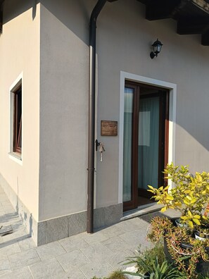 A building with a door, a window, a wall-mounted sign, and a potted plant.