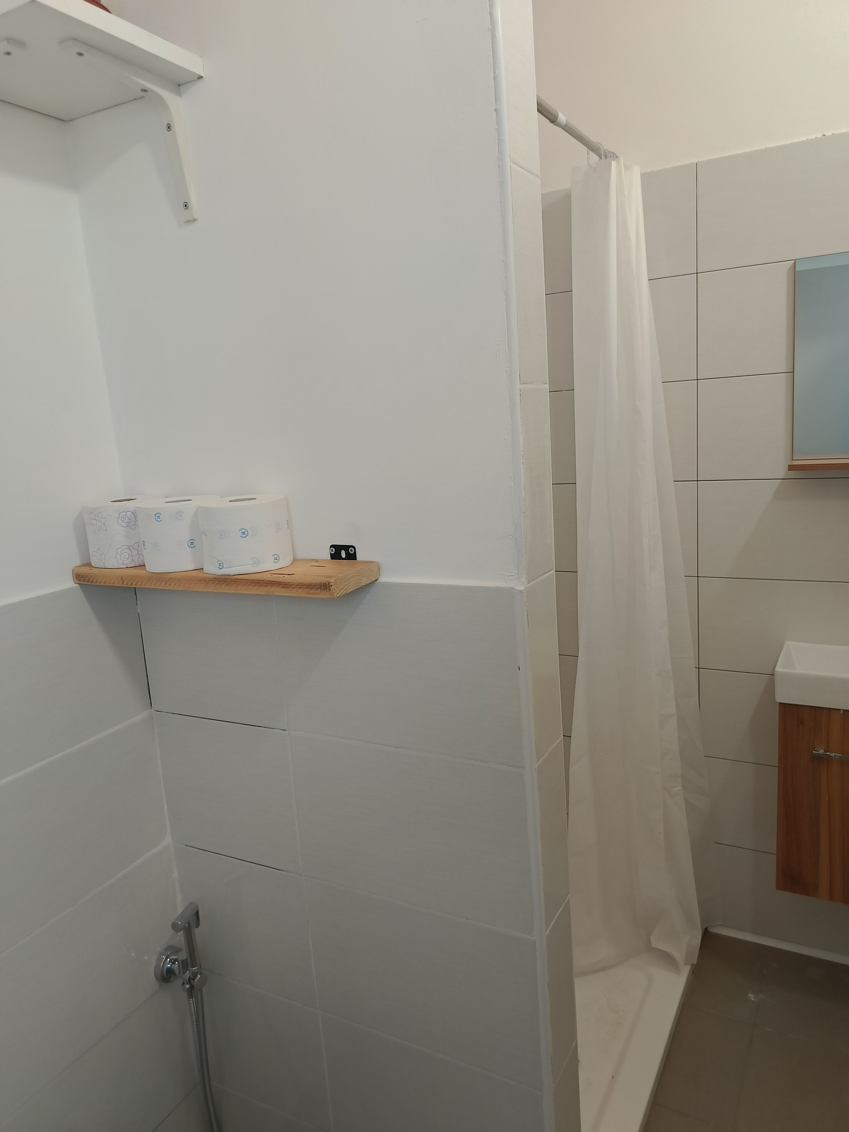 Ein Duschbereich mit einer Holzhilfe für Toilettenartikel, einer Duschbrause und einem Duschvorhang.