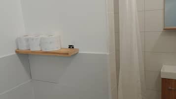 Ein Duschbereich mit einer Holzhilfe für Toilettenartikel, einer Duschbrause und einem Duschvorhang.