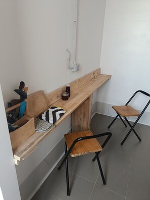 A small, compact room with a wooden bench, two chairs, and a wall-mounted heater.