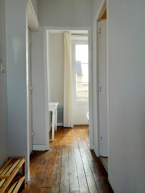 Ein Flur mit Holzboden, einer weißen Tür und Blick ins Freie.