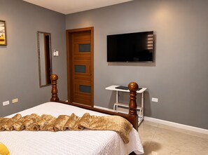 A bedroom with a bed, a television mounted on the wall, and a wooden door.