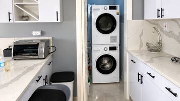 A modern kitchen with a built-in washer and dryer, a toaster, and a marble countertop.