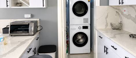 A modern kitchen with a built-in washer and dryer, a toaster, and a marble countertop.