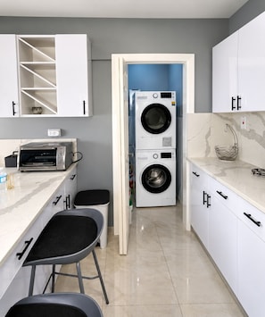 A modern kitchen with a built-in washer and dryer, a toaster, and a marble countertop.