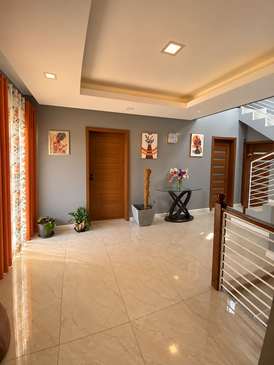 A spacious hallway with a marble floor, wooden doors, and a staircase with a glass railing.