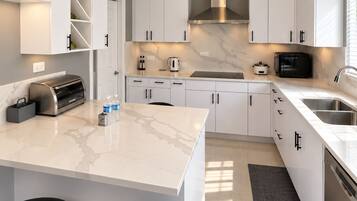 Una cocina moderna con armarios blancos, encimera de mármol y una isla integrada con taburetes de bar.