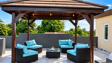 Un espace extérieur aménagé avec des meubles en osier et une pergola, le tout abrité.