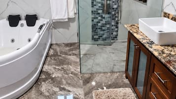 A modern bathroom with a glass-enclosed shower, a freestanding bathtub, and a marble floor.