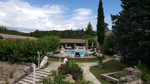Un'area piscina con lettini, una piscina in pietra e un giardino con vialetto in pietra.