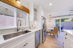 A modern kitchen with white cabinetry, a stainless steel refrigerator, and a built-in dishwasher. - Baby Beach 2BR, Walk to Everything W/Parking & AC! (Newport Beach)