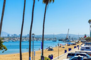 A beach with palm trees, a marina, and a city skyline in the background. - Baby Beach 2BR, Walk to Everything W/Parking & AC! (Newport Beach)