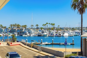 A marina with boats docked, a clear blue sky, and a row of houses in the background. - Baby Beach 2BR, Walk to Everything W/Parking & AC! (Newport Beach)