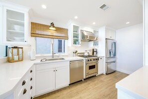 Eine moderne Küche mit weißen Schränken, einem eingebauten Herd, Backofen und Kühlschrank.