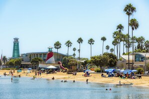 Ein Strand mit Palmen, einem Rettungsturm und einer Wasserrutsche.