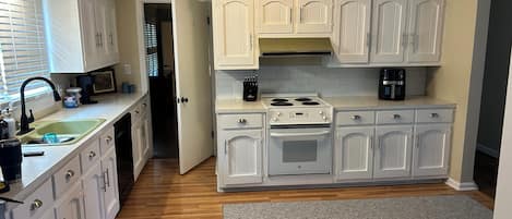 A kitchen with white cabinets, a built-in oven, a stove, and a sink.
