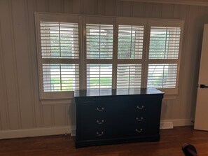 A room with a dark wooden dresser against a wall with white paneled trim.