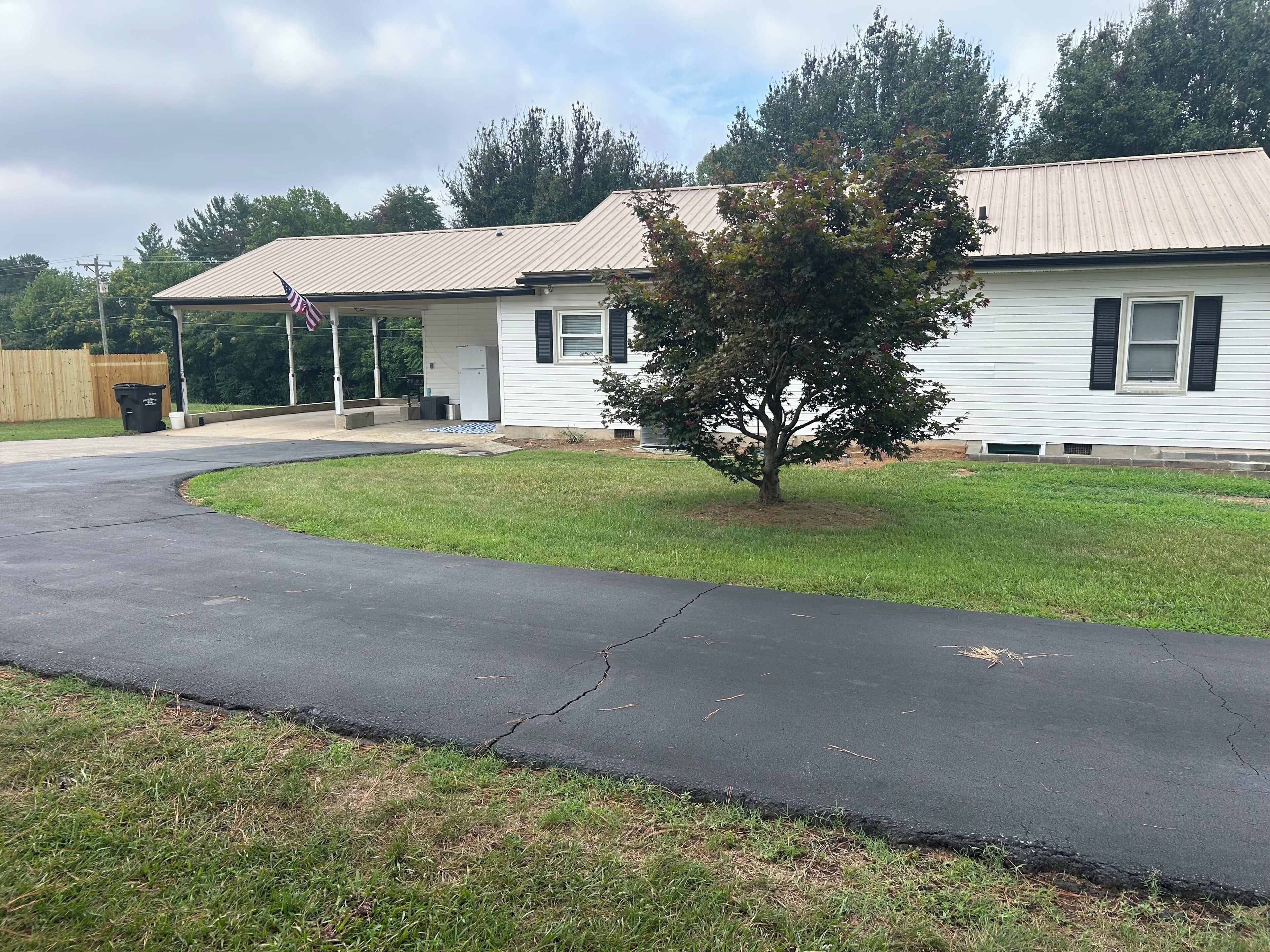 A single-story house with a front porch, a small tree in the yard, and a driveway leading to the entrance.