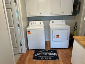 A laundry room with two washing machines and a self-service sign.
