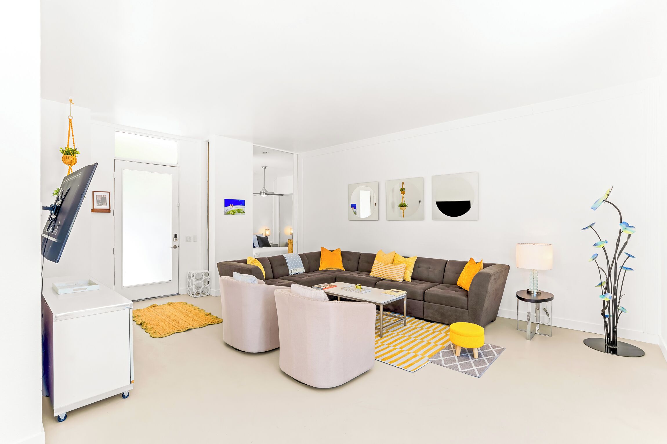 Un salon moderne comprenant un canapé, des poufs, une table basse, un téléviseur et une lampe.