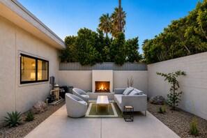 Eine moderne Außenpatio mit Kamin, Sitzgelegenheiten und Blick ins grüne Umland.