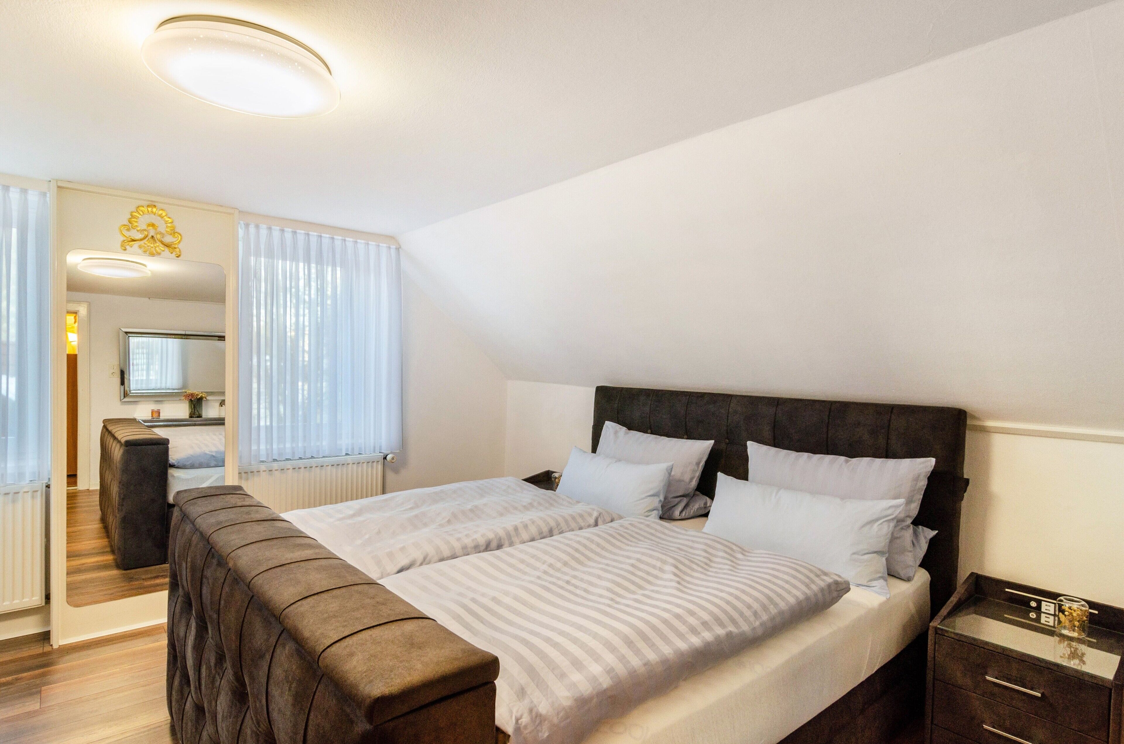 Een hotelkamer met een bed, nachtkastje en een spiegel.