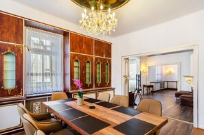 Un comedor formal con una larga mesa, sillas, un candelabro y un espejo grande.