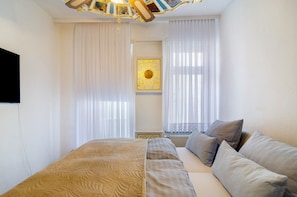 Un dormitorio con cama, cortinas, un cuadro enmarcado y un radiador.