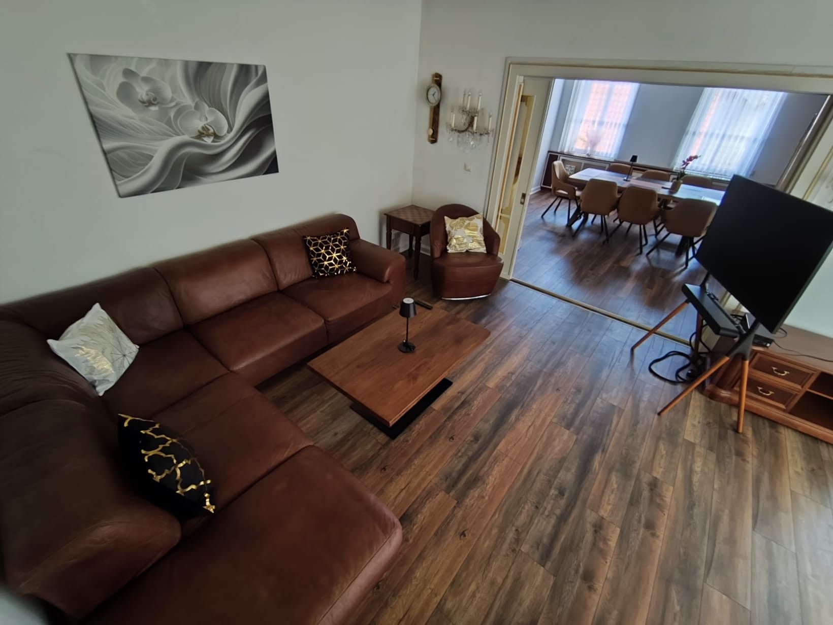 Ein modernes Wohnzimmer mit einem braunen Ledersofa, einem Couchtisch und einem Flachbildfernseher.