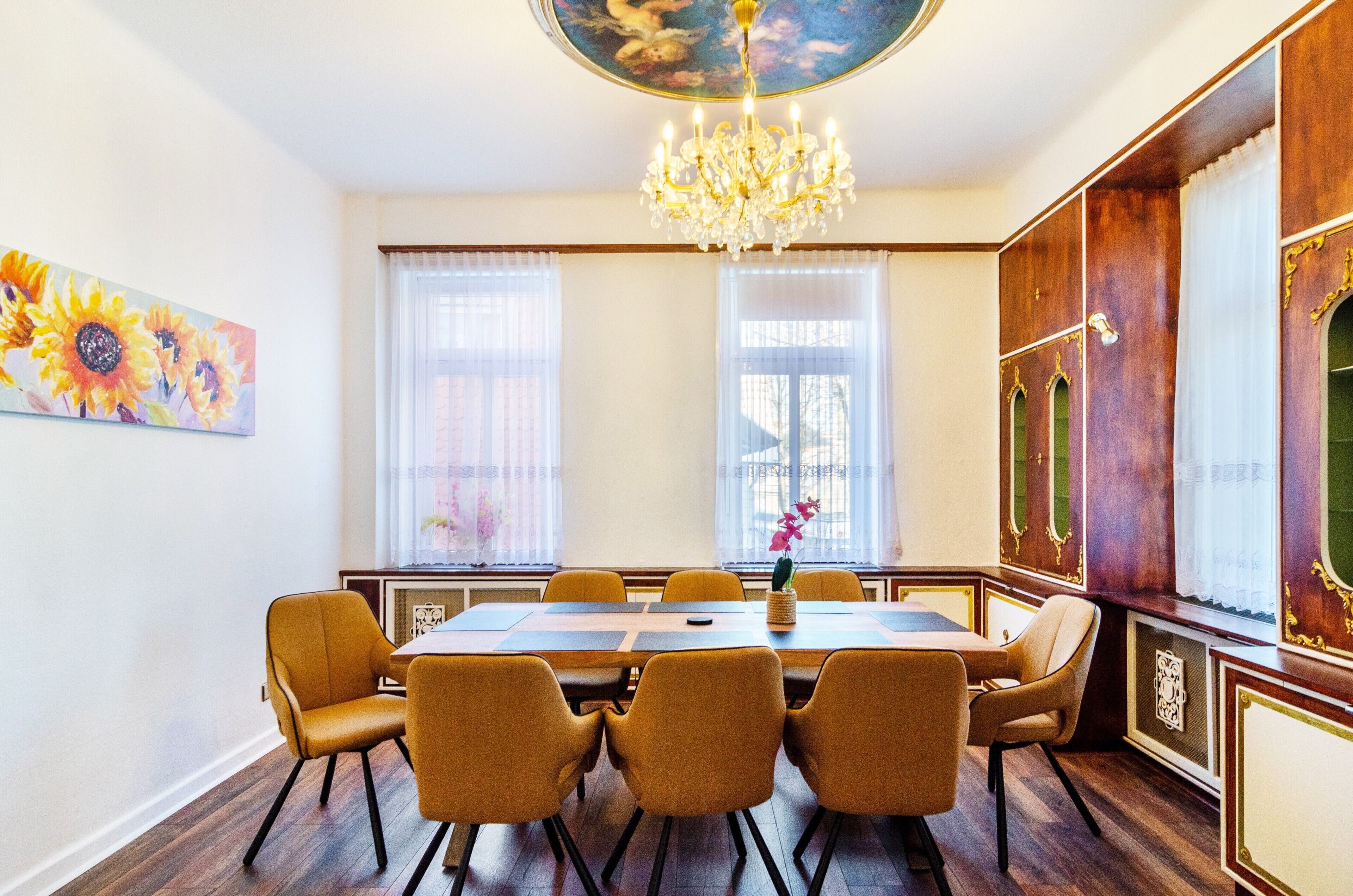 Ein Esszimmer mit einer Kandelaber, einem Tisch mit Stühlen und einem Gemälde an der Wand.