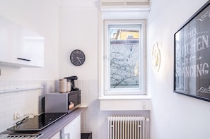Eine moderne Küche mit Einbauofen, Kaffeemaschine und einem Fenster mit Blick auf kahle Bäume.