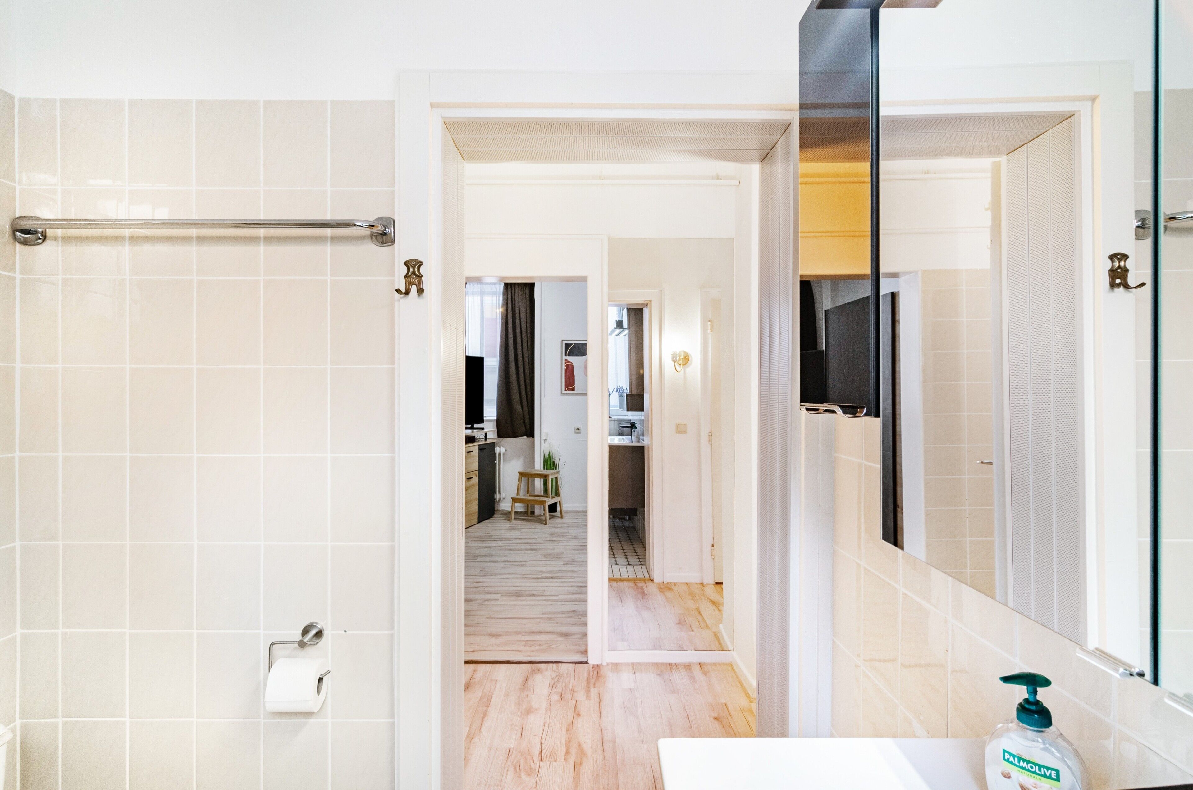 Ein Badezimmer mit Toilettenpapierhalter, Spiegel und Handseife.