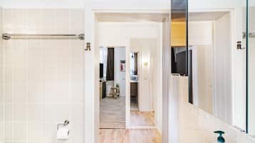 Ein Badezimmer mit Toilettenpapierhalter, Spiegel und Handseife.